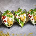 Crispy fish tacos with cabbage, creamy sauce, salsa, lime, and fresh cilantro